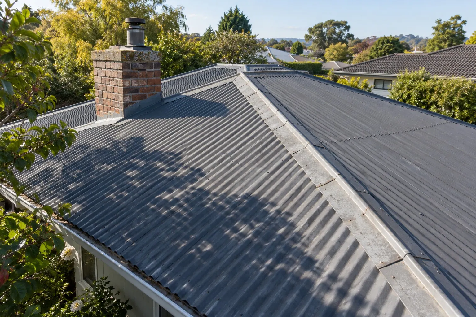 Tree and chimney shadows across a corrugated metal roof