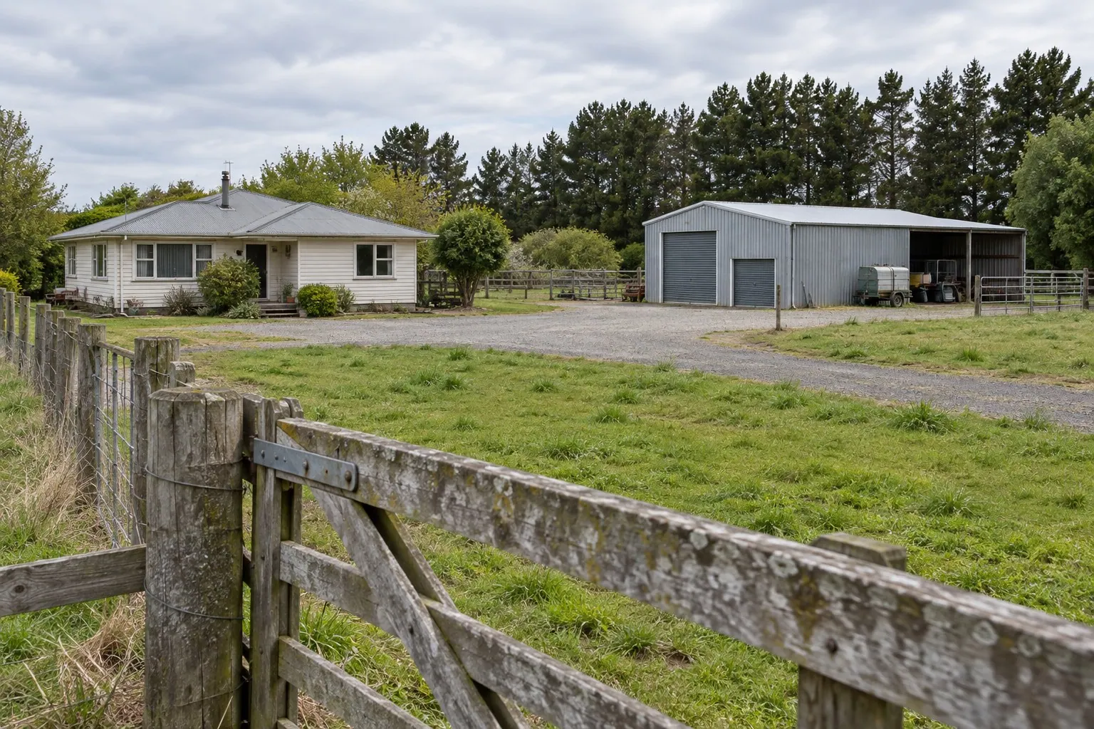House and separate corrugated iron shed beyond a fenced grass paddock